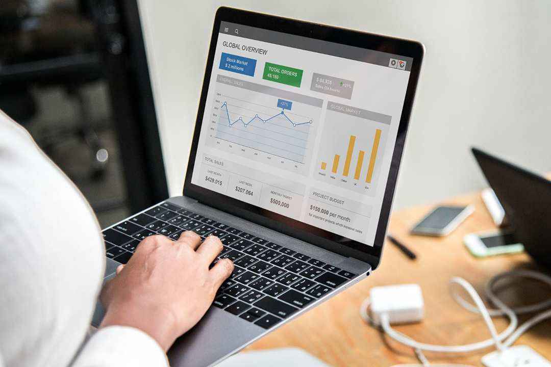 A person holding a laptop with analytics on the screen.