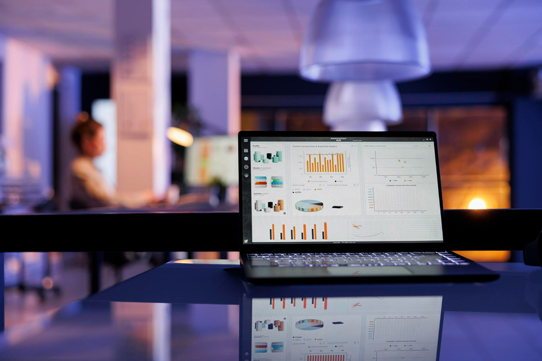 A laptop on an office desk with analytics on the screen.