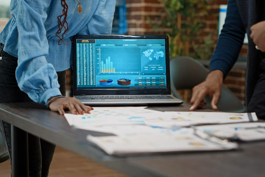 Two office workers pointing at papers on a desk.
